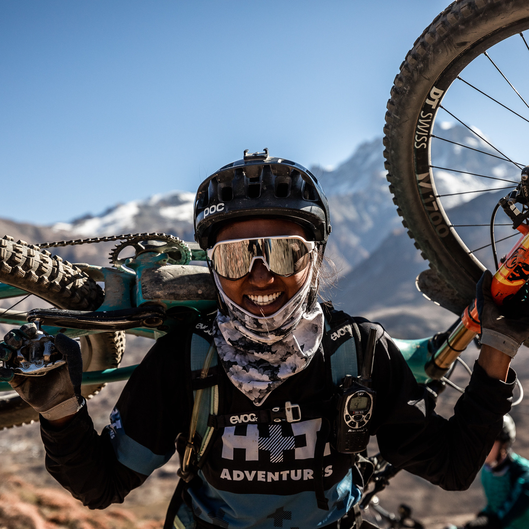 Mountain biker carrying bike in scenic mountainous terrain, wearing helmet and goggles. Adventure sports, cycling in rugged landscape, outdoor exploration. Mountain Bike United.