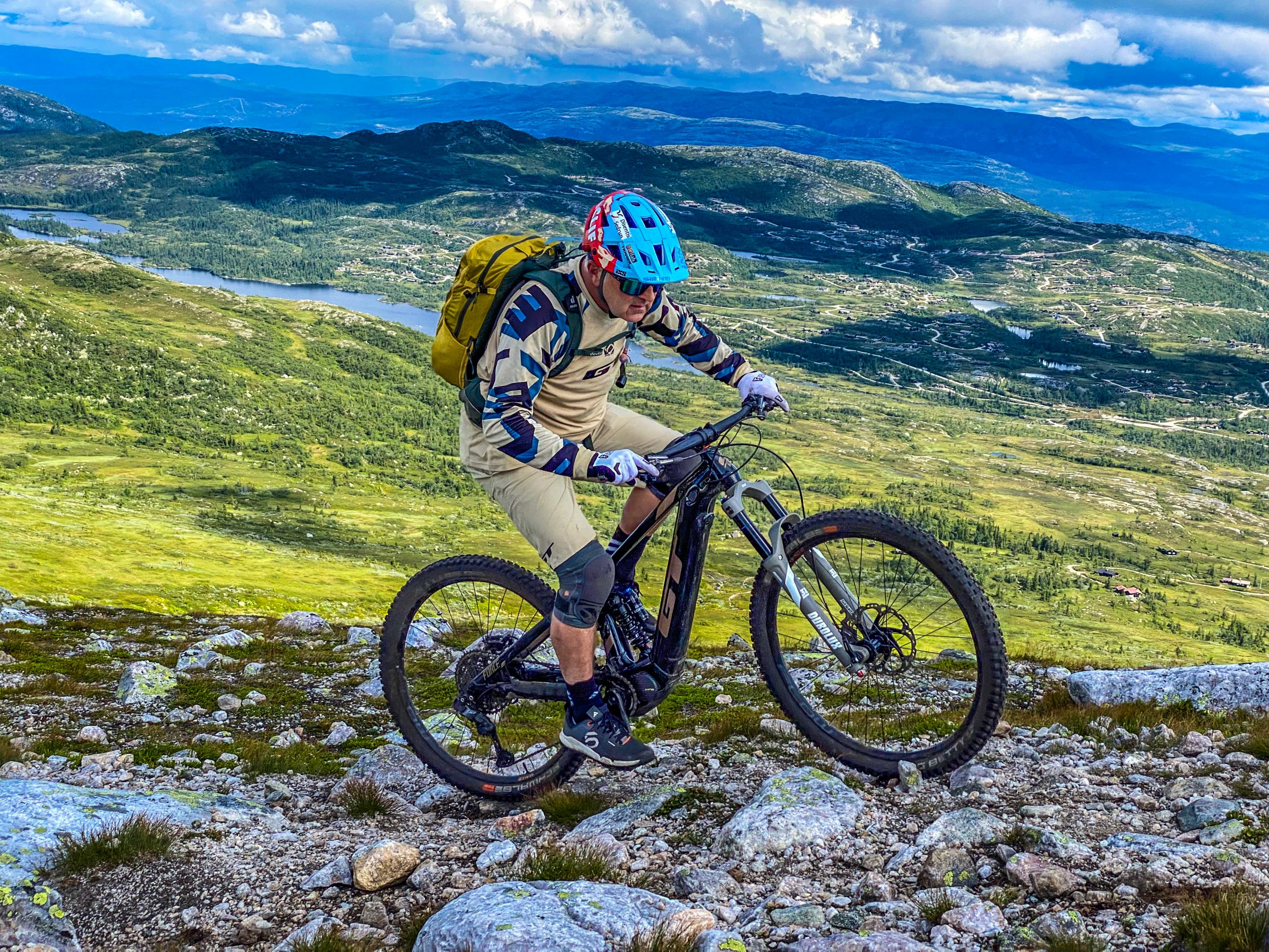 Mountain biker traversing rocky terrain with a scenic backdrop, highlighting
