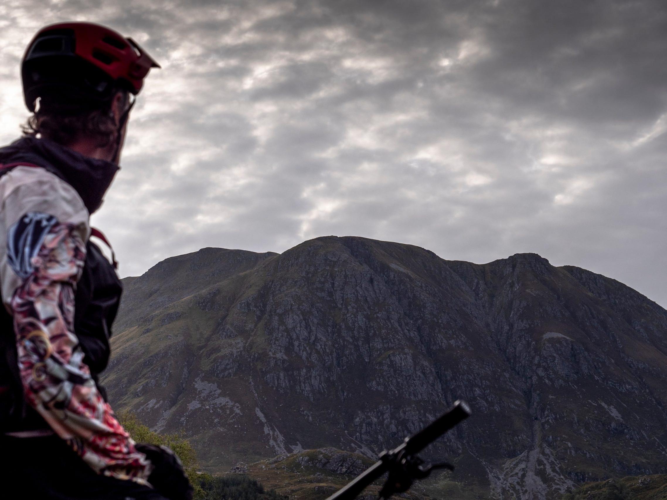 Mountain biker overlooking scenic mountains under a cloudy sky, highlighting outdoor adventure, cycling, and nature exploration. Mountain Bike United.