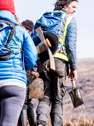Volunteers building mountain biking trails with shovels, enhancing paths tracked via mountain biking app for improved outdoor adventure. Mountain Bike United.
