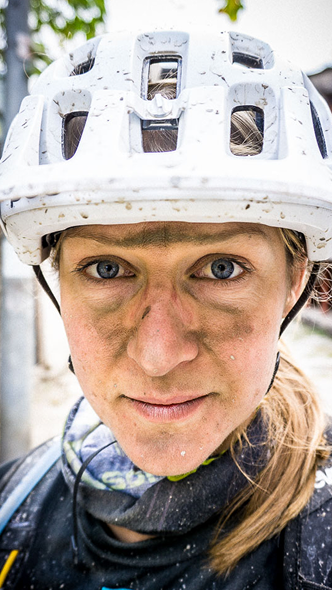 Female mountain biker wearing a helmet covered in dirt, representing passion for outdoor adventures. Mountain biking app. Mountain Bike United.