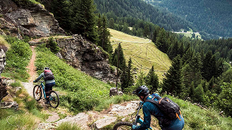 Mountain bikers navigate a rugged trail in the forested mountains, showcasing features of a new mountain biking app for outdoor adventure tracking. Mountain Bike United.