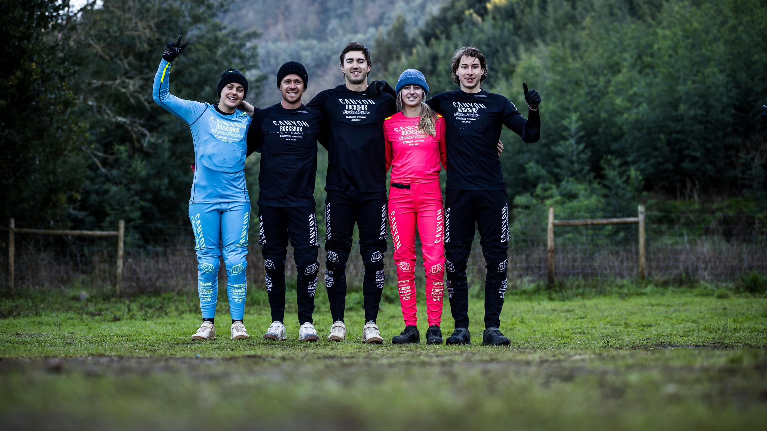 Canyon CLLCTV Gravity Team members posing outdoors in branded attire, showcasing teamwork and unity in a forested setting. Mountain Bike United.