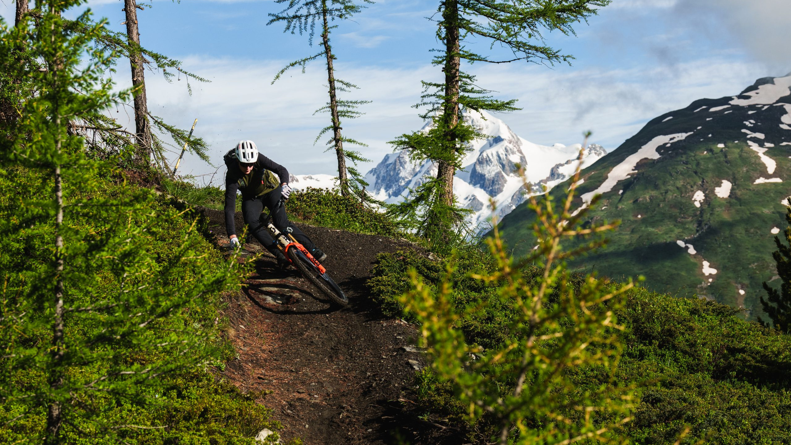 Mountain biker on a trail with Alpine views in Italy, showcasing thrilling adventure; ideal for keywords Scotty Laughland Italy mountain biking. Mountain Bike United.