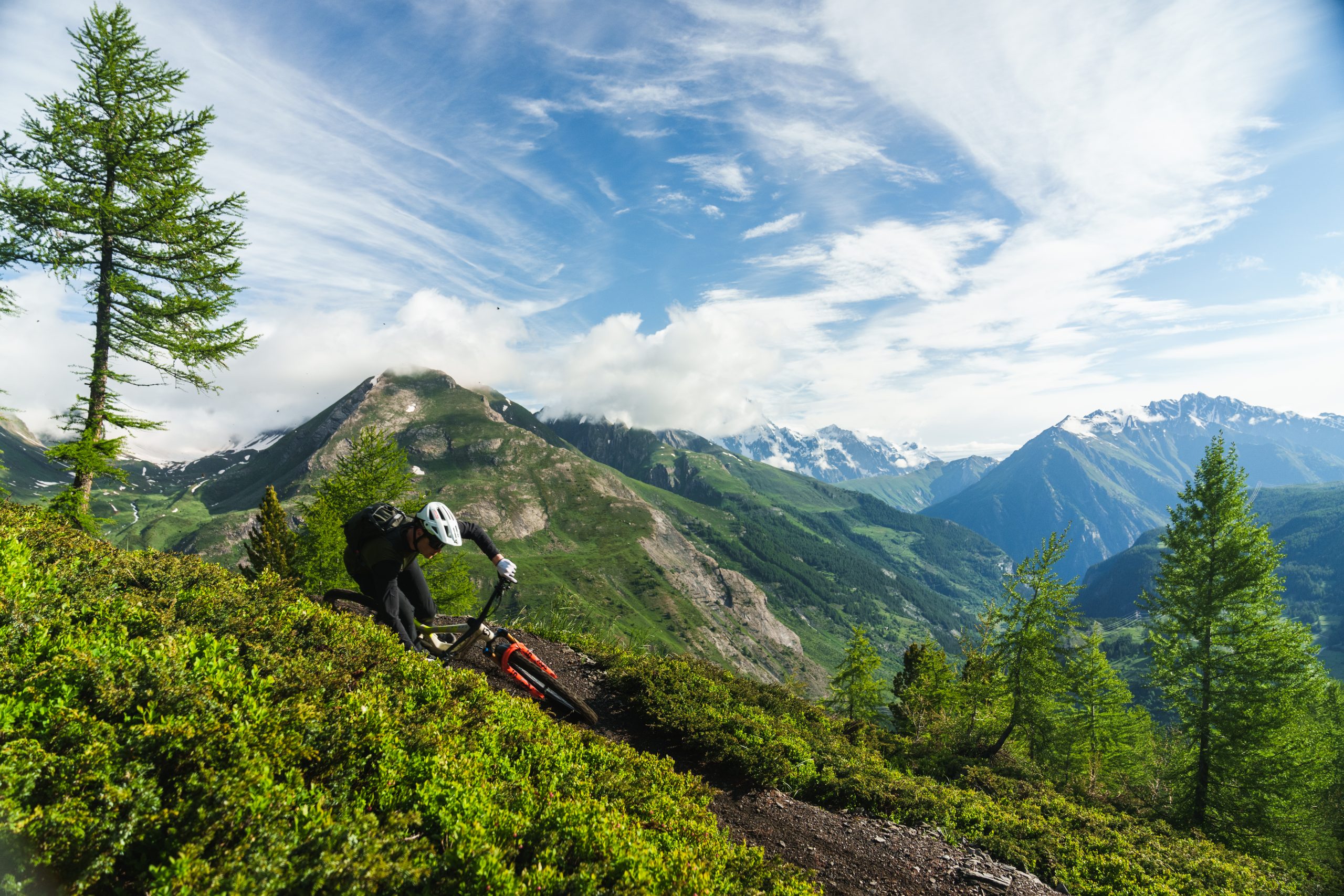 Scotty Laughland mountain biking through scenic trails in Italy with lush greenery and mountainous landscape. Mountain Bike United.