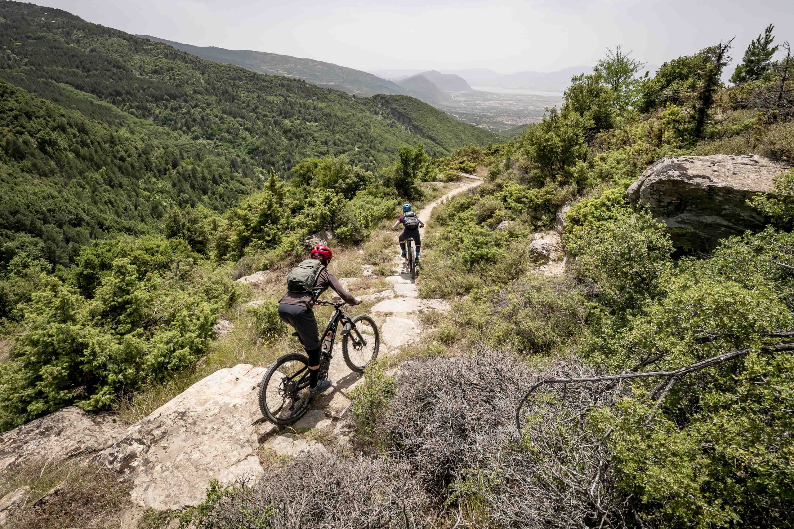 Mountain bikers on a trail through scenic hills, showcasing adventure and community connections via a mountain bike community app. Mountain Bike United.