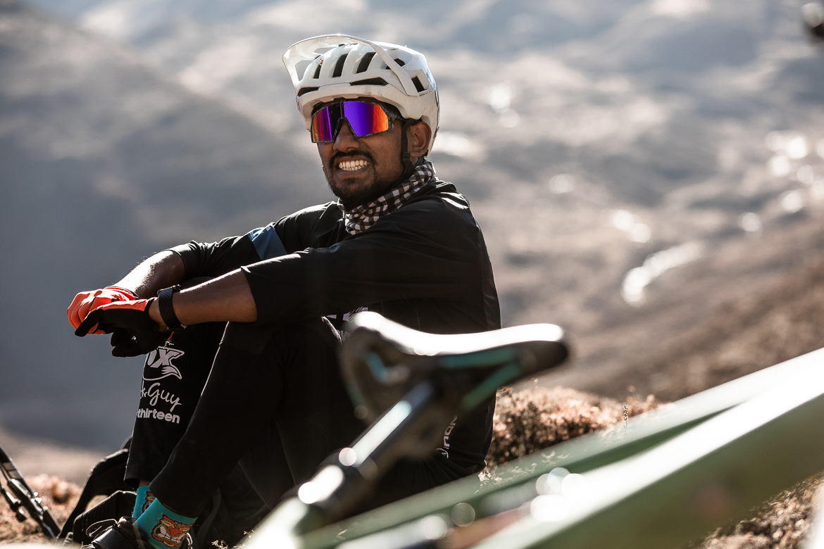 Mountain biker resting on a trail with helmet and sunglasses, surrounded by scenic mountainous terrain. Outdoor cycling adventure concept. Mountain Bike United.