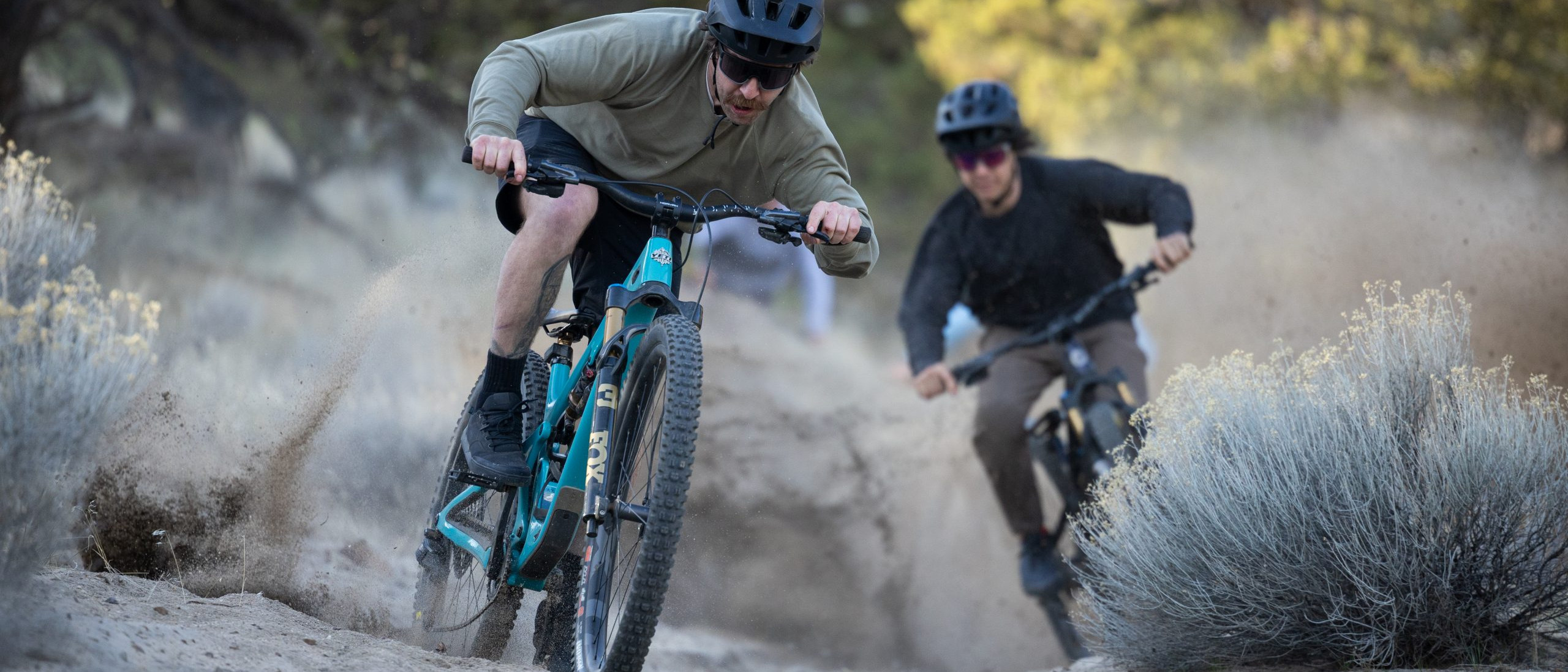 Two mountain bikers racing on a dirt trail, showcasing speed and skill, ideal for organizing MTB events with thrilling outdoor adventure. Mountain Bike United.