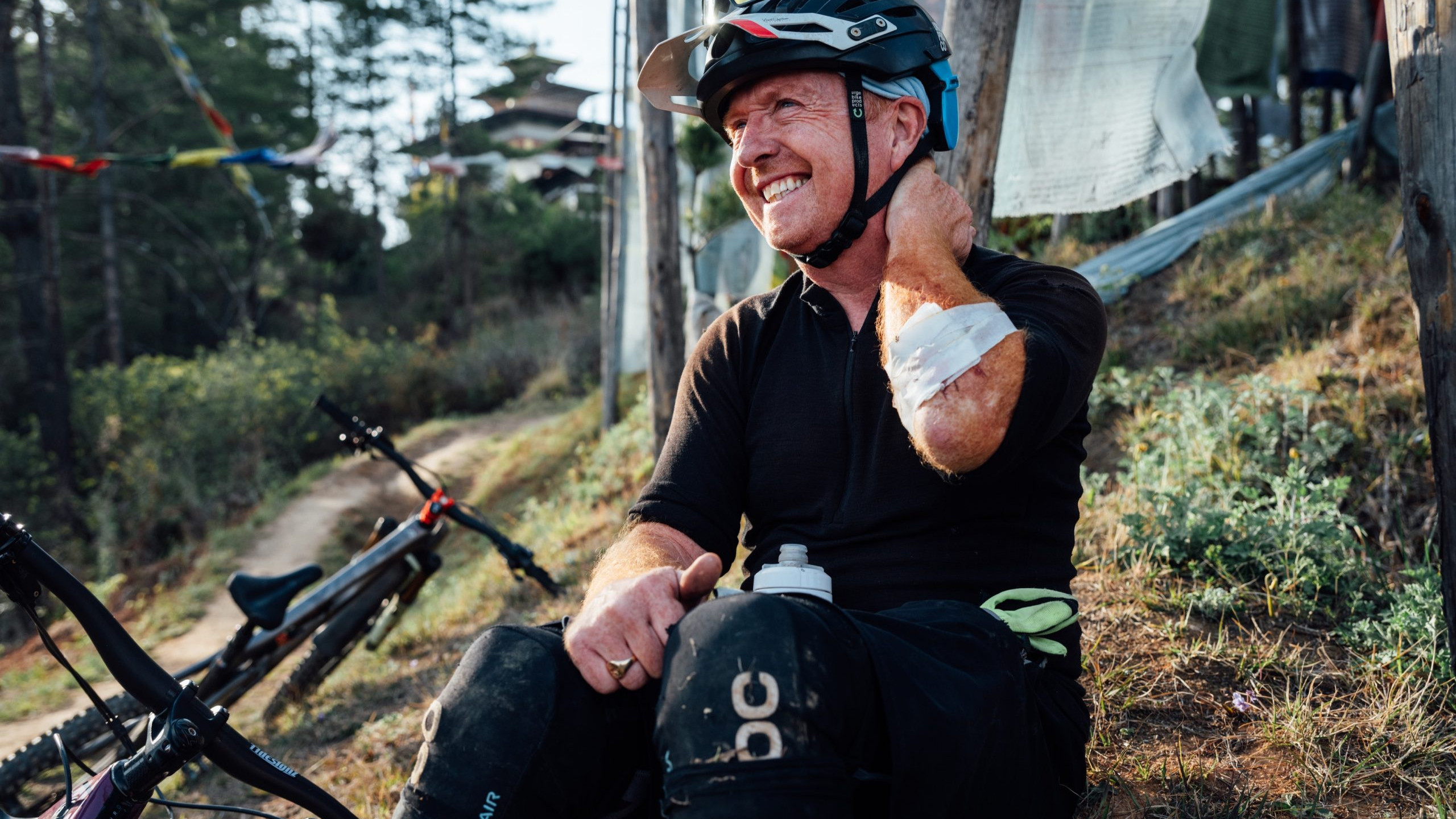 Mountain biker resting on trail with bike, showcasing mountain bike industry tools and gear for outdoor cycling adventures. Mountain Bike United.