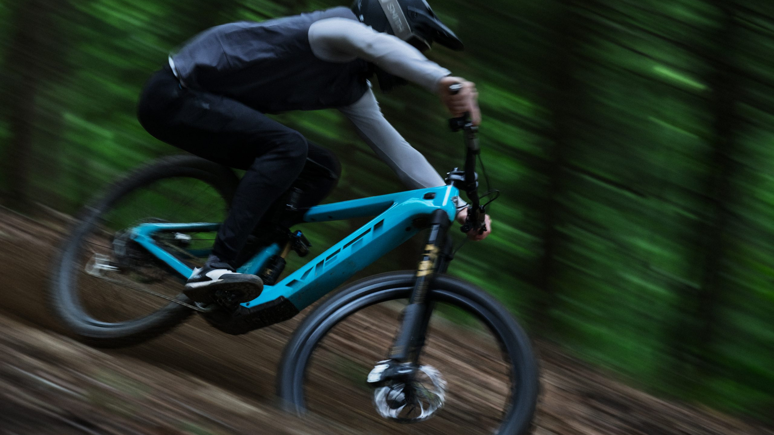 Mountain biker speeding through a forest trail, showcasing mountain bike industry tools and gear for performance and durability. Mountain Bike United.