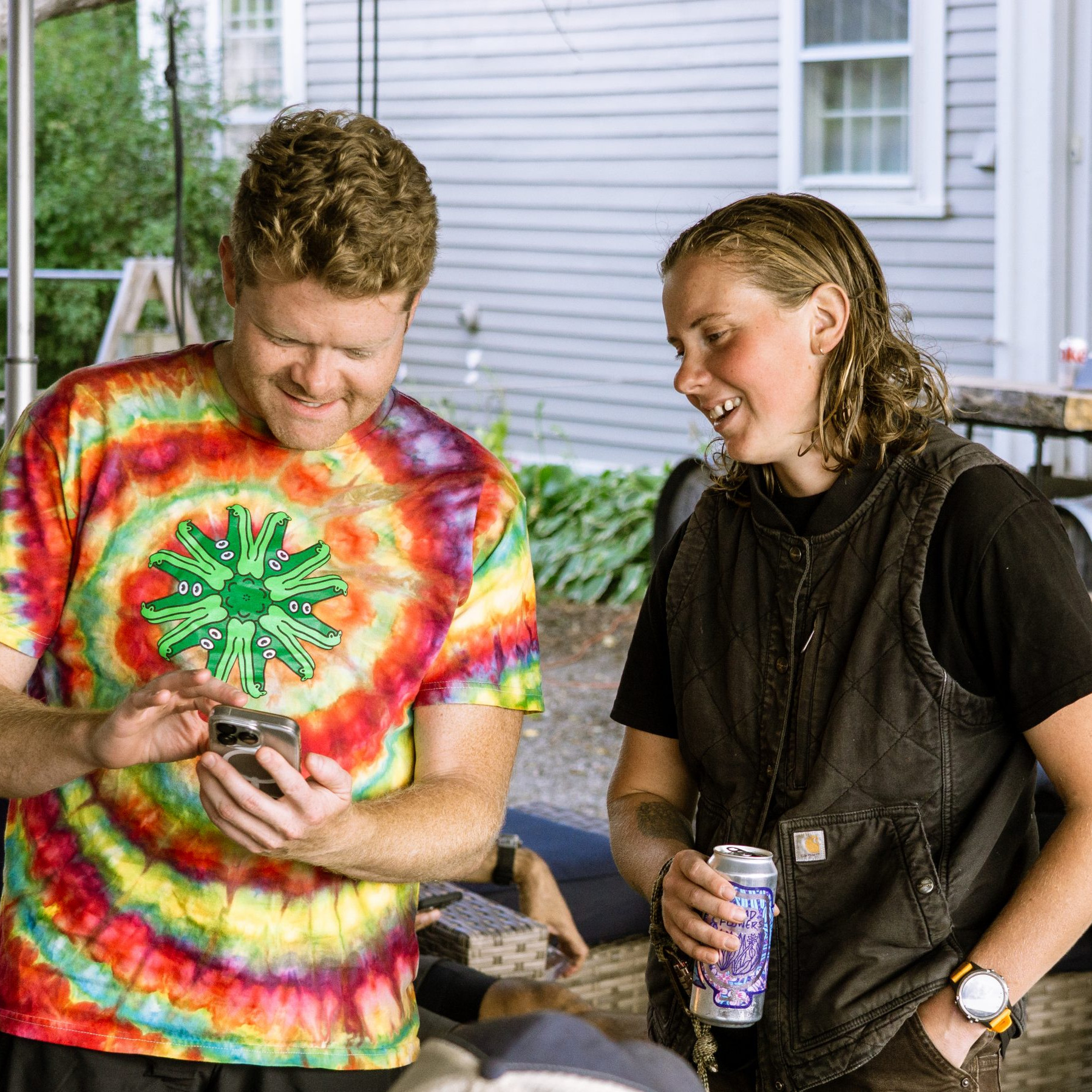 People discussing event planning on a smartphone, ideal for organizing an MTB event. Casual outdoor setting enhances focus on mountain biking coordination. Mountain Bike United.
